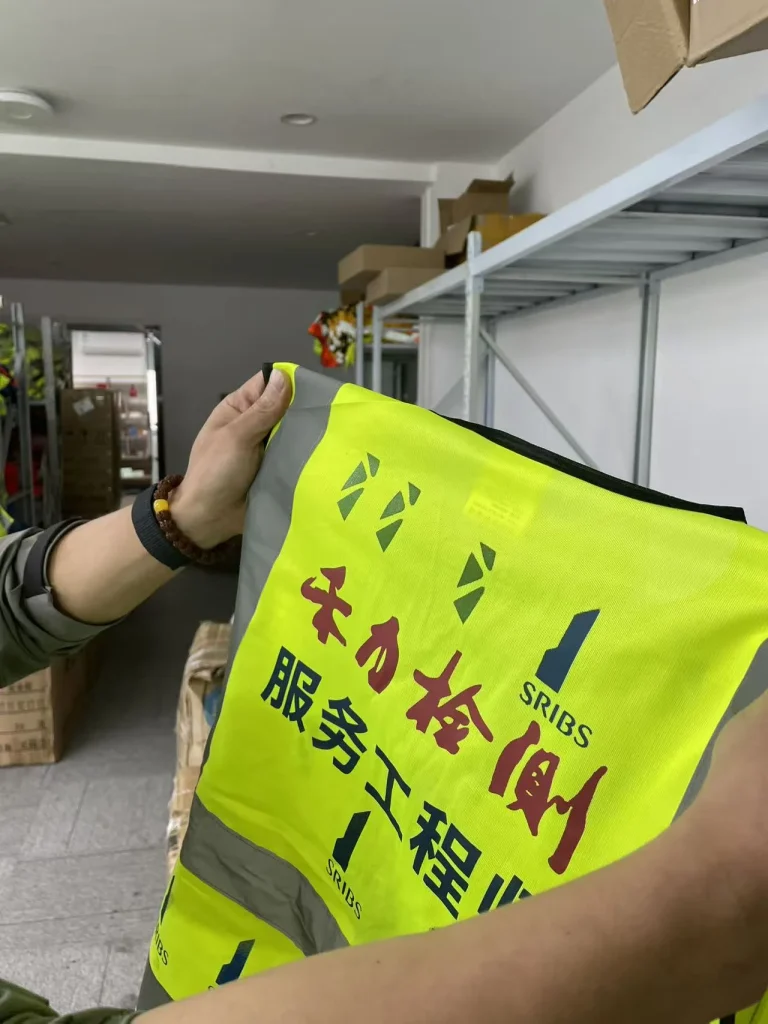 手持黄绿色反光背心，展示多色图文与 SRIBS 标识