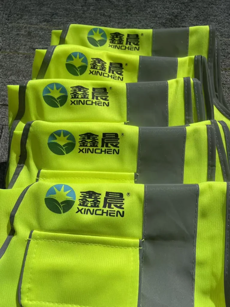 黄绿色反光背心上印有彩色图形、鑫晨和 XINCHEN 字样